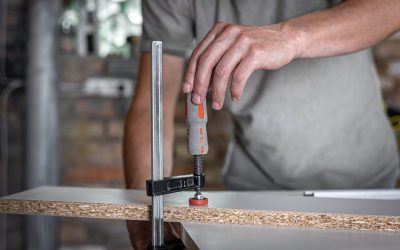 Carpenter doing wood work using clamping hand tool in his workshop.